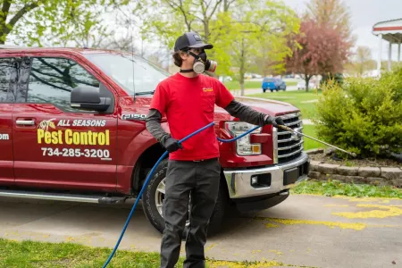 all seasons exterminator spraying the perimeter of a home